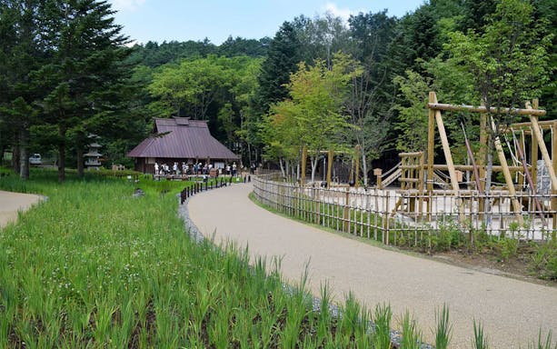 Pathway leading to traditional building at Shinobi No Sato Ninja Village, surrounded by trees and play area.