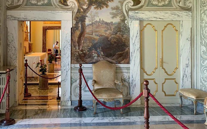 Elegant interior of Castle Gandolfo with ornate chair and mural.