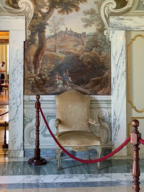 Elegant interior of Castle Gandolfo with ornate chair and mural.