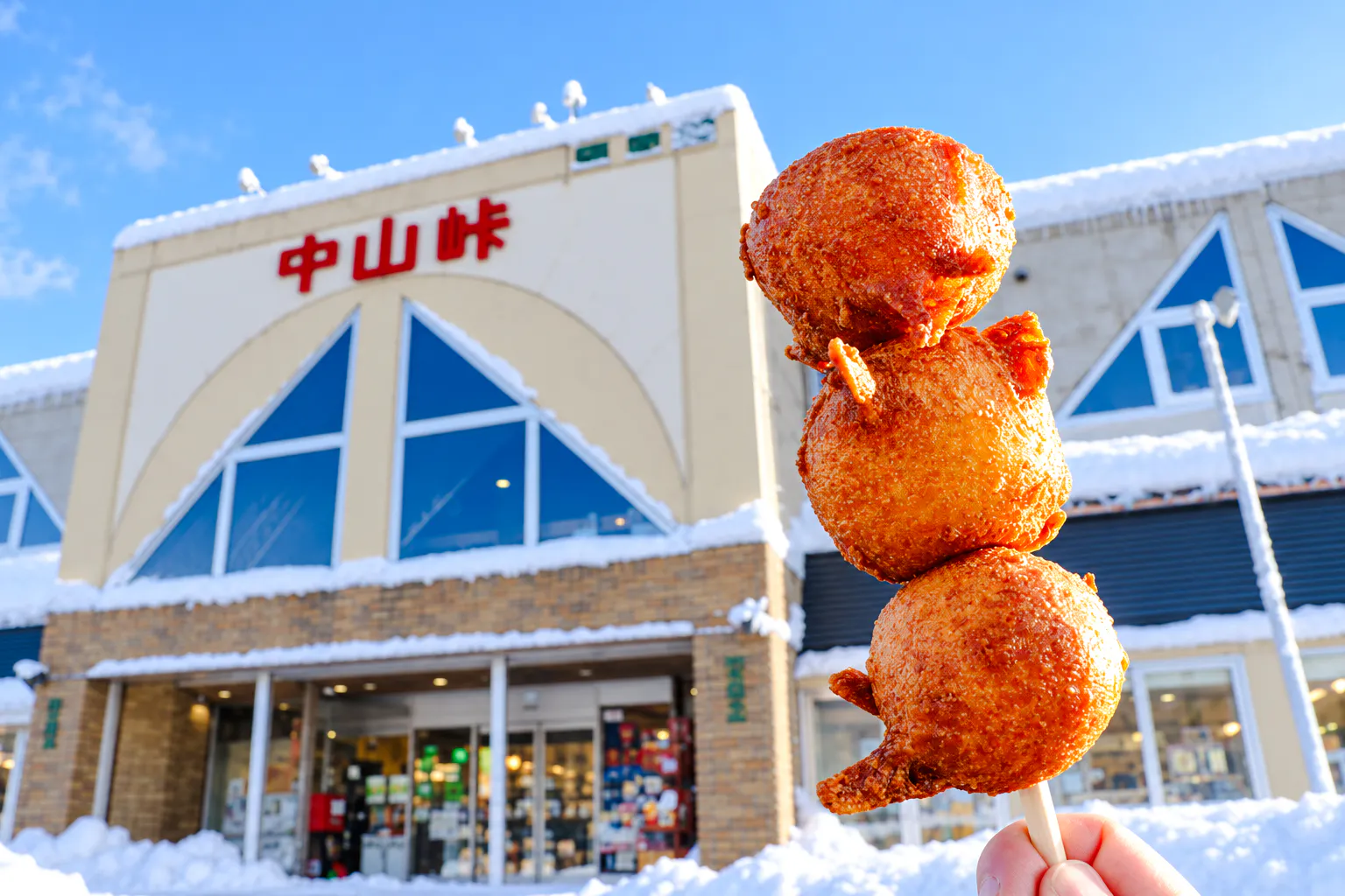 Skewered fried snacks in front of a snow-covered building in Sapporo, Hokkaido.