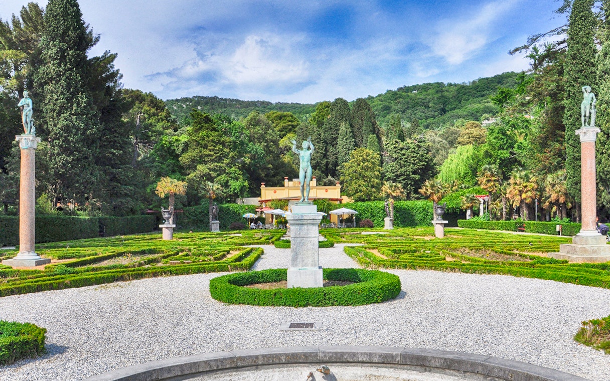 Miramare Castle Garden with statues and manicured hedges in a lush green setting.