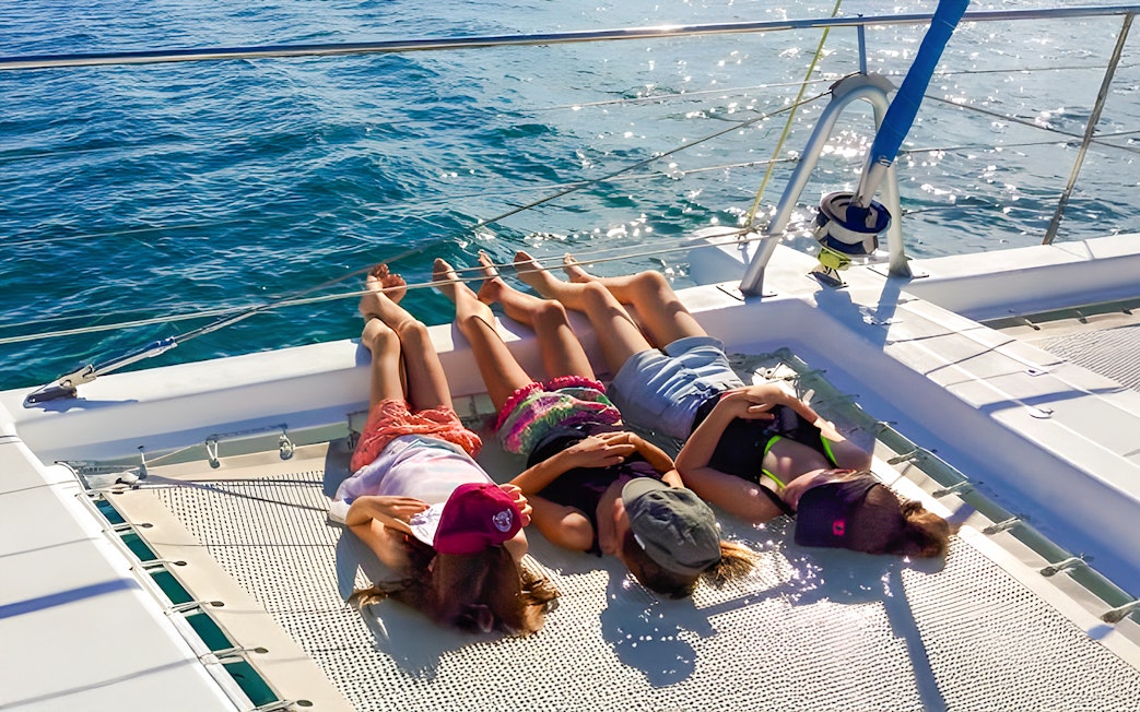 People relaxing on a catamaran net during an eco cruise near Fraser Island, K'gari.