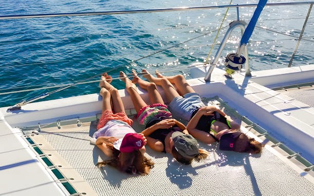 People relaxing on a catamaran net during an eco cruise near Fraser Island, K'gari.