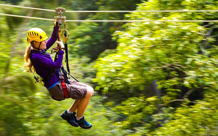 Guest zip lining through lush forest on Kohala Canopy Adventure, Hawaii.