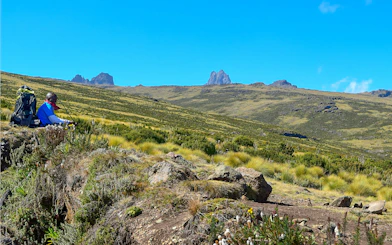 Hiker resting with backpack in Mount Kenya's volcanic landscape, Kenya.