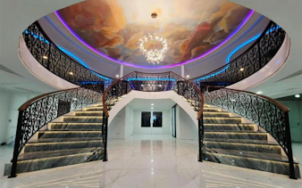 Elegant staircase with ornate railings and ceiling mural on Noah Cruise, Bangkok.