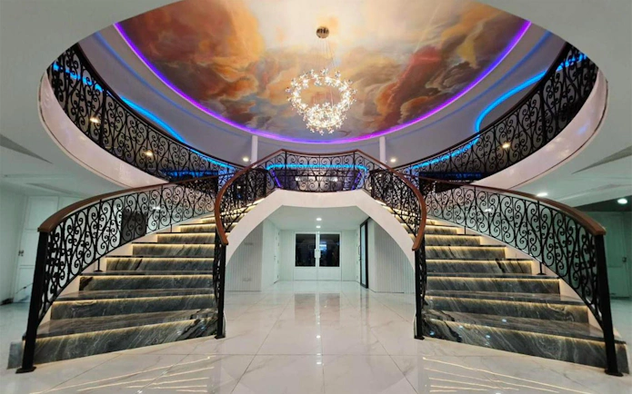 Elegant staircase with ornate railings and ceiling mural on Noah Cruise, Bangkok.