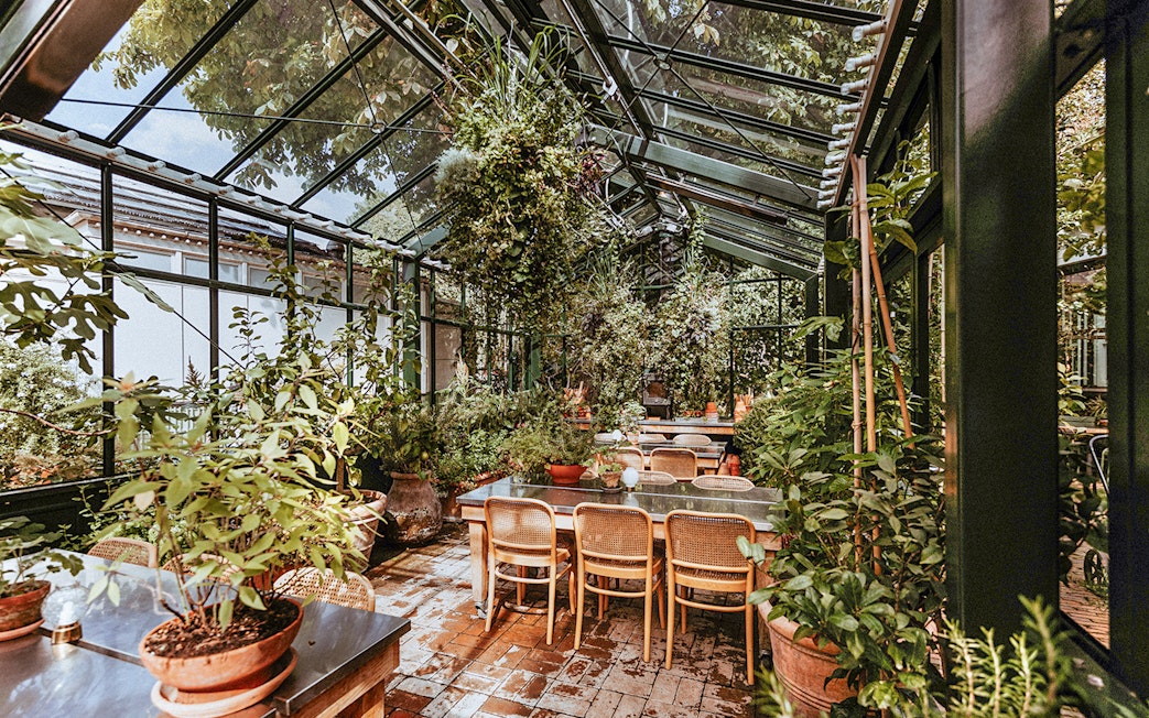 Greenhouse dining area with plants at Tivoli Gardens, Copenhagen.