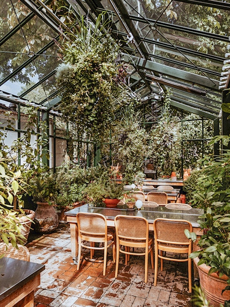 Greenhouse dining area with plants at Tivoli Gardens, Copenhagen.