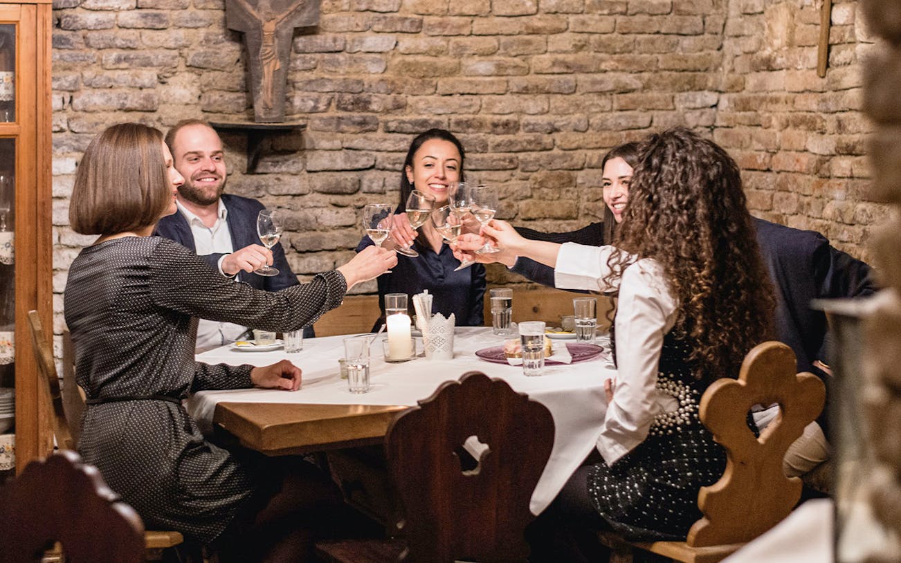 Group toasting wine glasses in a rustic cellar during a guided tasting tour.