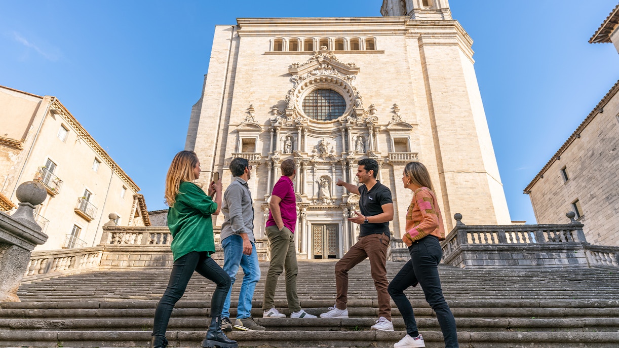 Tourists with guide in front of Girona Cathedral, Spain, exploring historic architecture.