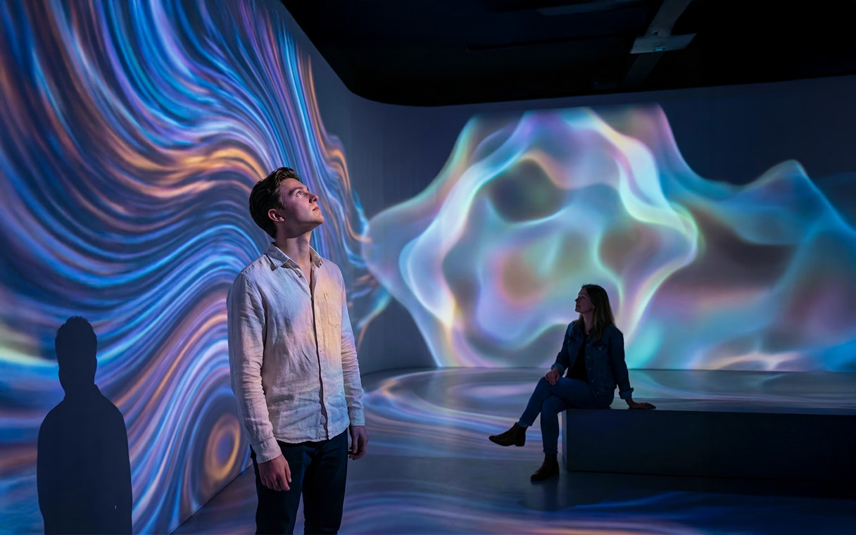 Guests experiencing abstract digital projections in an immersive exhibit.
