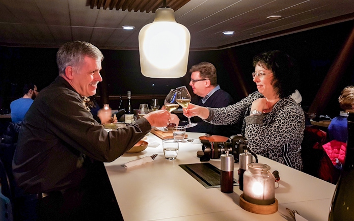 Guests toasting with wine glasses on an Aurora Boreal dinner cruise.