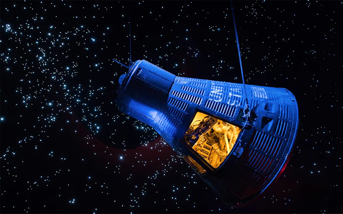 Space capsule exhibit at Space Center Houston against a starry backdrop.