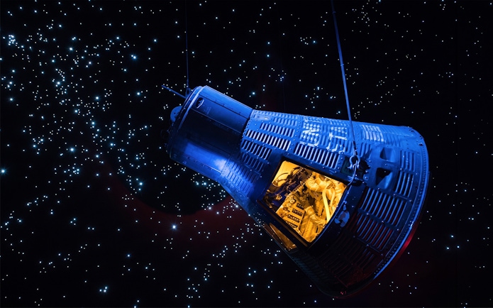 Space capsule exhibit at Space Center Houston against a starry backdrop.