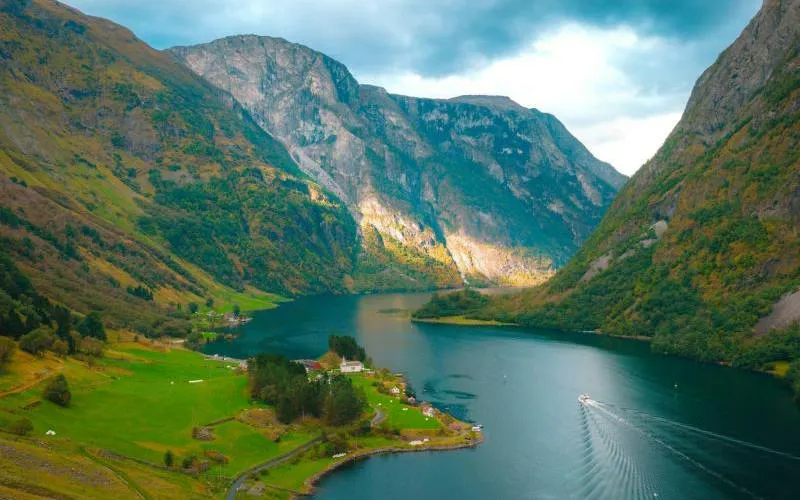 Breathtaking view of Nærøyfjord with a boat cruising, surrounded by steep mountains, part of Bergen to Flåm tour.