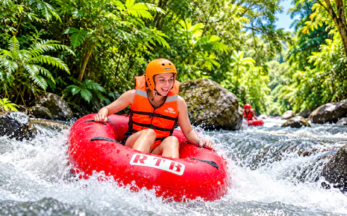 Tubing adventure on Pekerisan River, Bali amidst lush greenery.