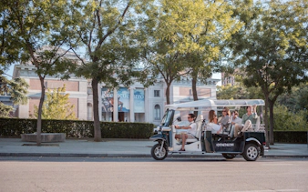 Tourists on an electric tuk-tuk tour in front of a museum in Madrid.