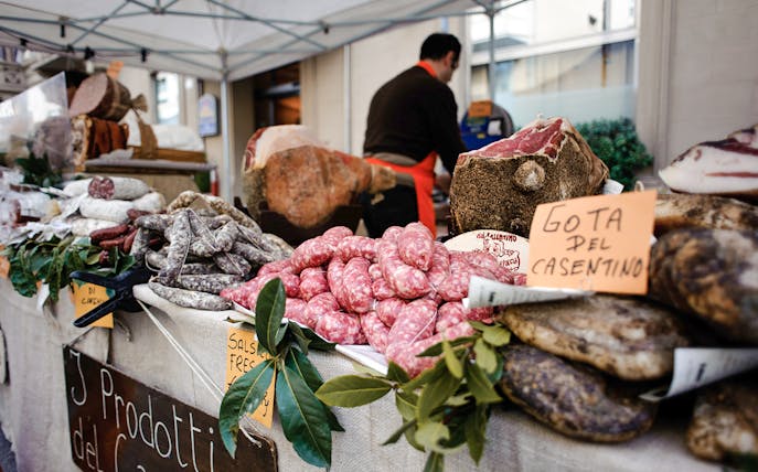 Tuscan market stall with cured meats and sausages for cooking class lunch.