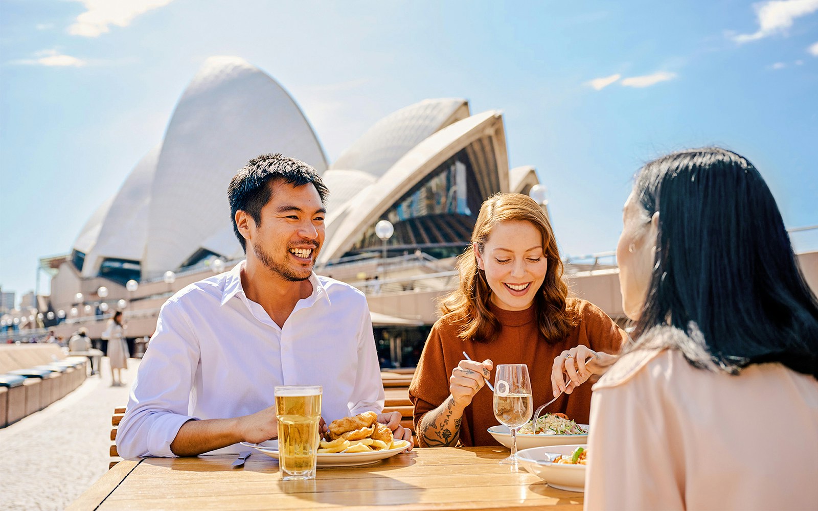 People dining outdoors near Sydney Opera House.