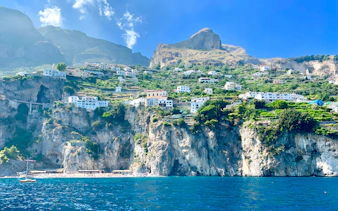 Cliffside view of Positano with colorful buildings and lush greenery, seen from the sea.