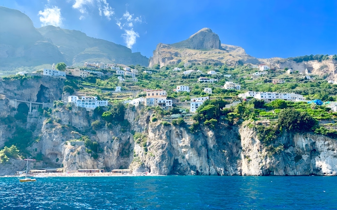Cliffside view of Positano with colorful buildings and lush greenery, seen from the sea.