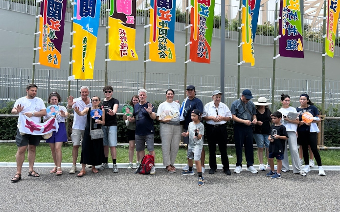 Spectators outside Nagoya Grand Sumo Tournament venue with colorful banners.