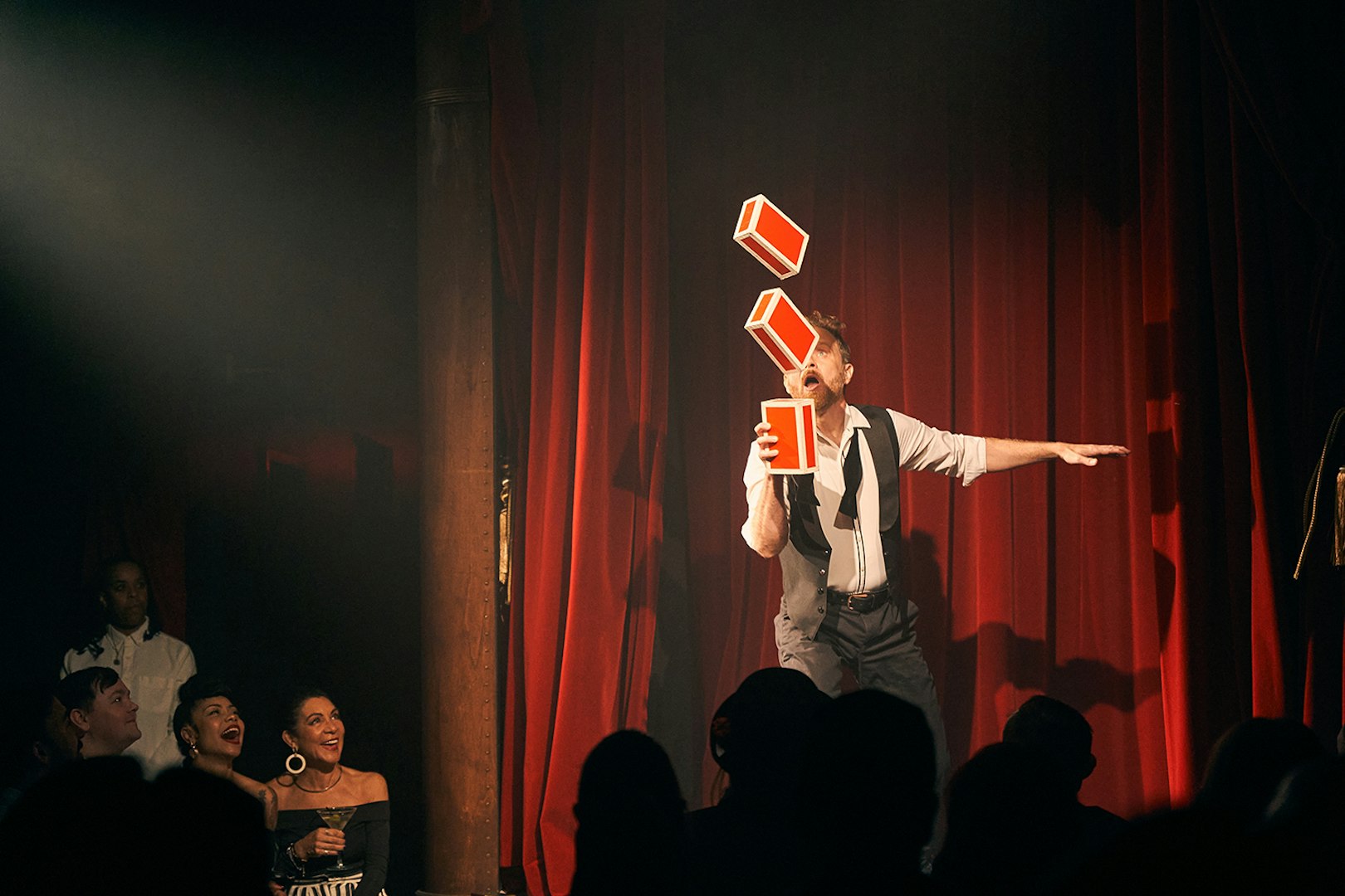 Performer juggling boxes on stage at Miss Behaves: Maverick's Variety Show.