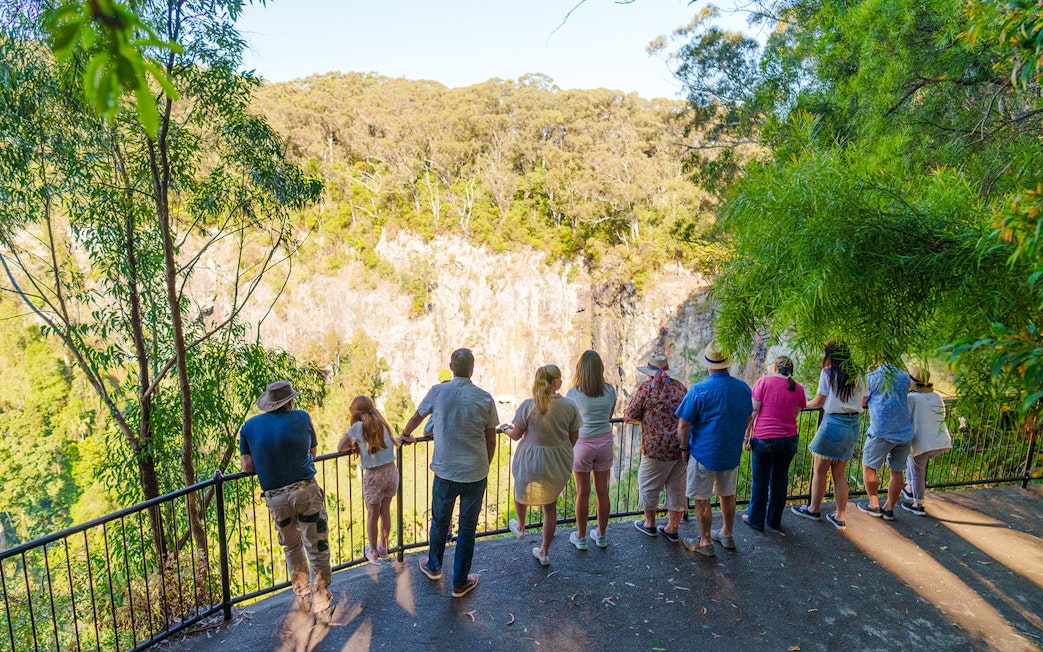 Tourists viewing Springbrook Waterfalls from a lookout on the Natural Bridge tour.