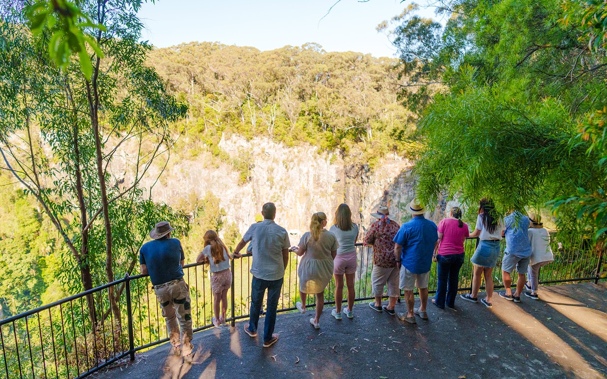Tourists viewing Springbrook Waterfalls from a lookout on the Natural Bridge tour.