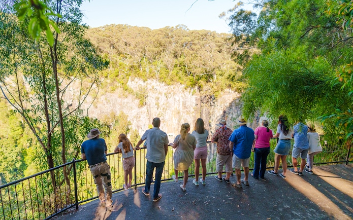 Tourists viewing Springbrook Waterfalls from a lookout on the Natural Bridge tour.