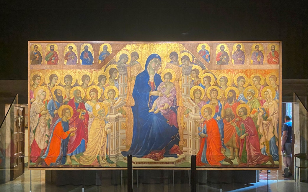 Alt text: "Tourists viewing the Maestà by Duccio at the Siena Duomo Complex in Siena, Italy.