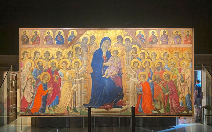 Alt text: "Tourists viewing the Maestà by Duccio at the Siena Duomo Complex in Siena, Italy.