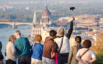 Tourists taking photos of Budapest Parliament from a viewpoint.