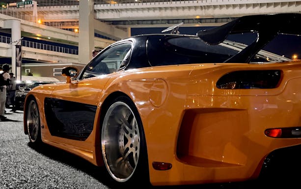 Orange sports car at Daikoku PA in Tokyo, showcasing local car culture.