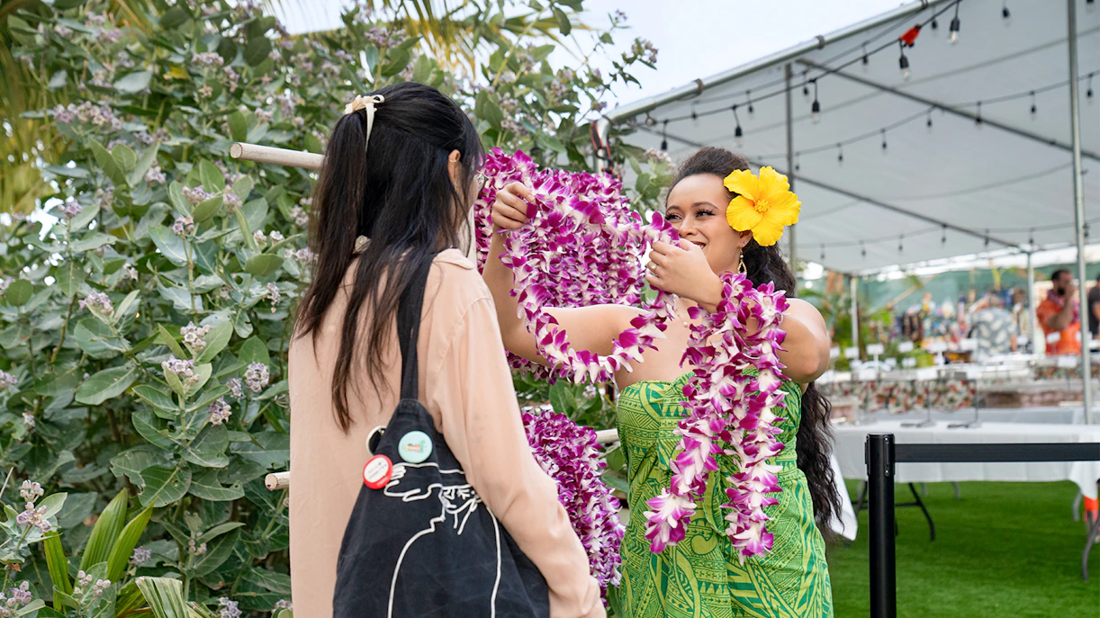 Staff member presenting a lei to a guest at Mauka Warriors Luau, Hawaii.