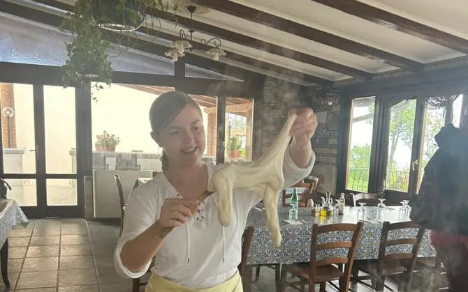 Person stretching mozzarella in Amalfi Coast farmhouse cooking class.