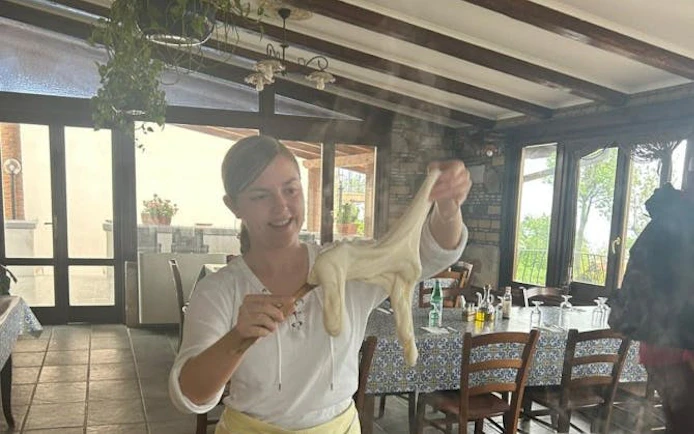 Person stretching mozzarella in Amalfi Coast farmhouse cooking class.