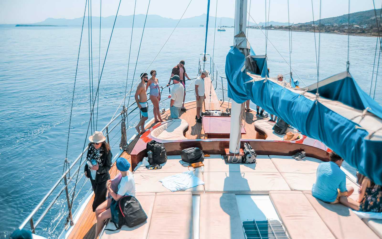 Friends enjoying a sunny day on a sailboat cruise with scenic ocean views.