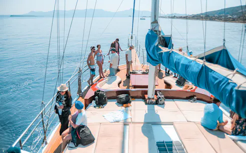 Friends enjoying a sunny day on a sailboat cruise with scenic ocean views.