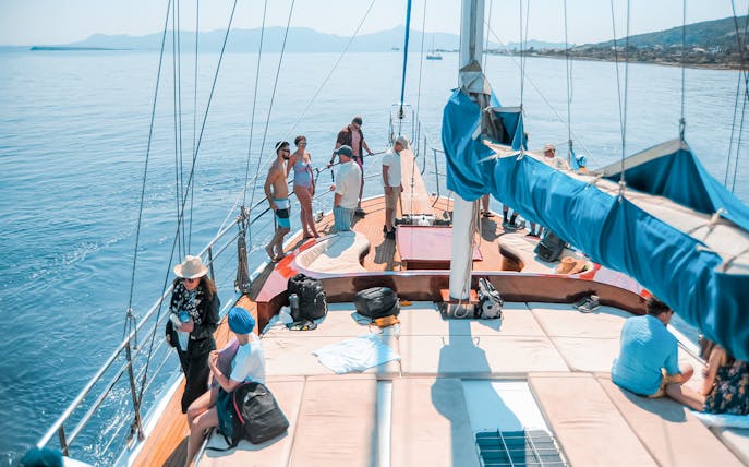 Friends enjoying a sunny day on a sailboat cruise with scenic ocean views.