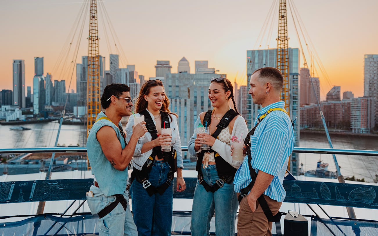 Guests enjoying drinks atop the O2 with a view of London's skyline at sunset.