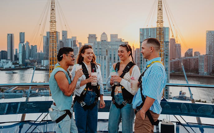 Guests enjoying drinks atop the O2 with a view of London's skyline at sunset.