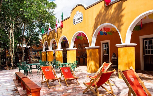 Courtyard with colorful chairs and arches in Cancun jungle setting.