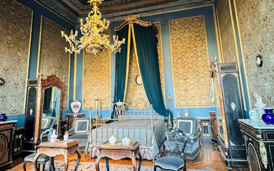 Luxurious bedroom in Chapultepec Castle, featuring ornate furniture and a grand chandelier.
