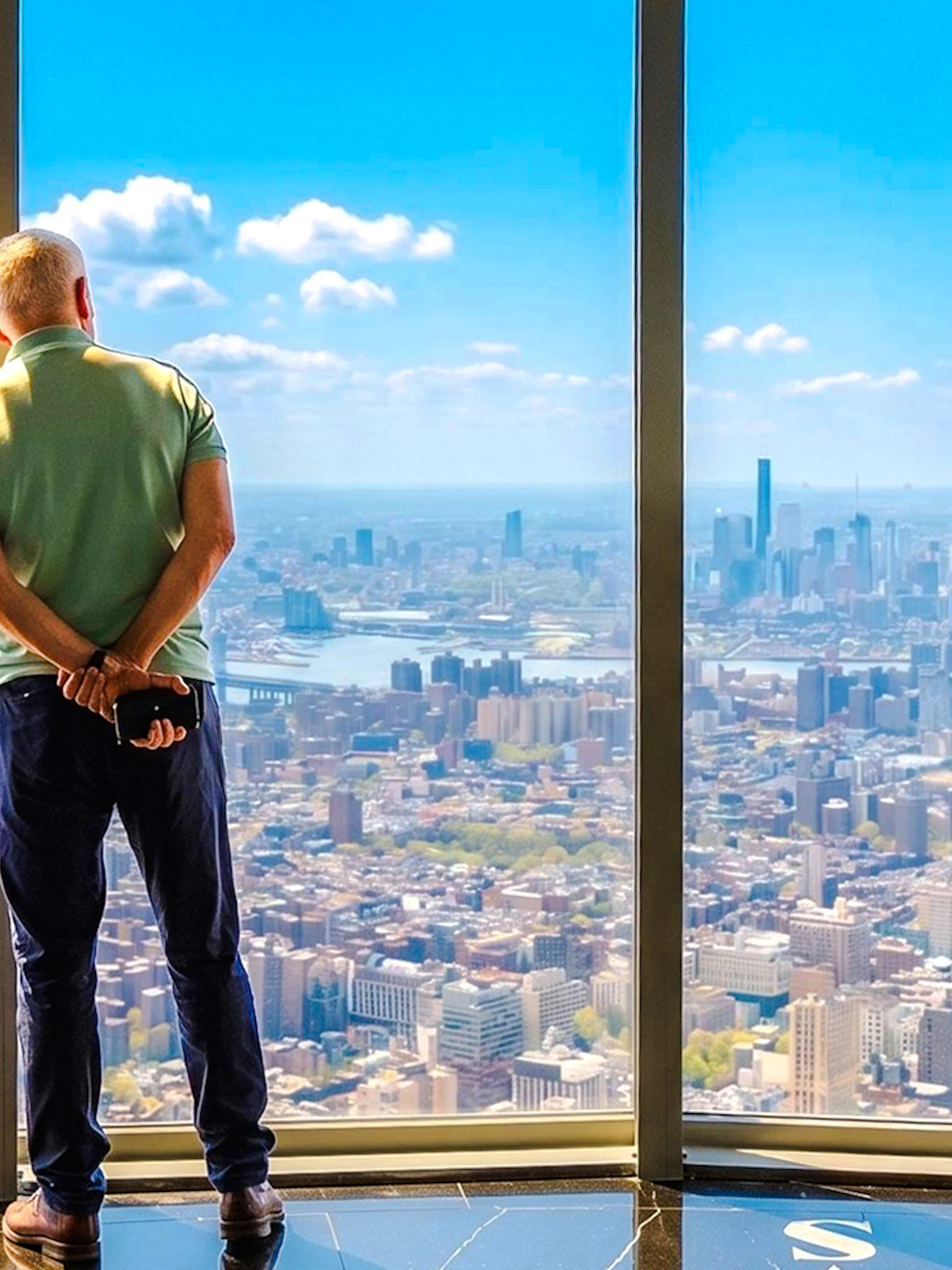 Man viewing New York City skyline from Empire State Building observatory.