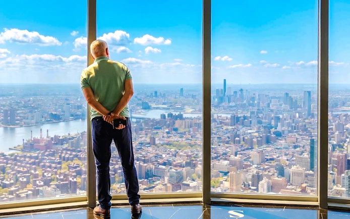 Man viewing New York City skyline from Empire State Building observatory.