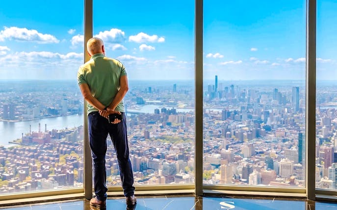 Man viewing New York City skyline from Empire State Building observatory.