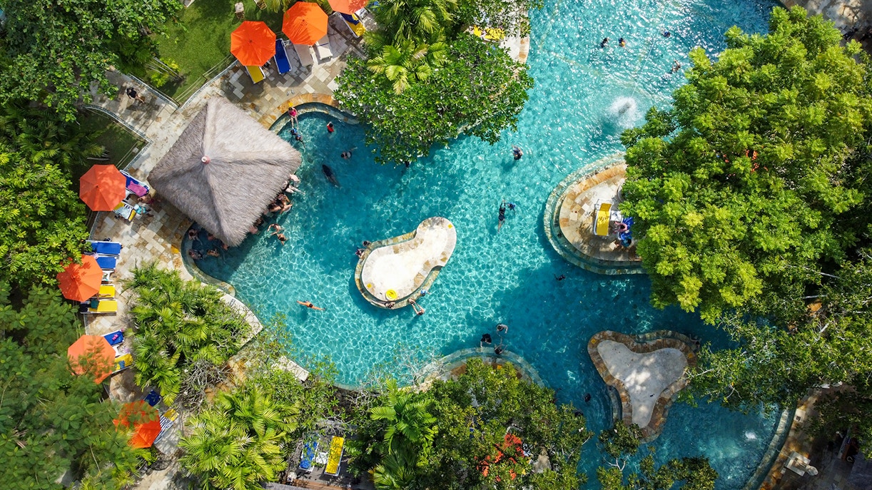 Aerial view of the Pleasure Pool at Waterbom Bali water park, featuring slides and surrounding greenery
