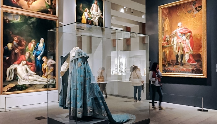 Royal Collections Gallery in Spain displaying regal attire and historical paintings.